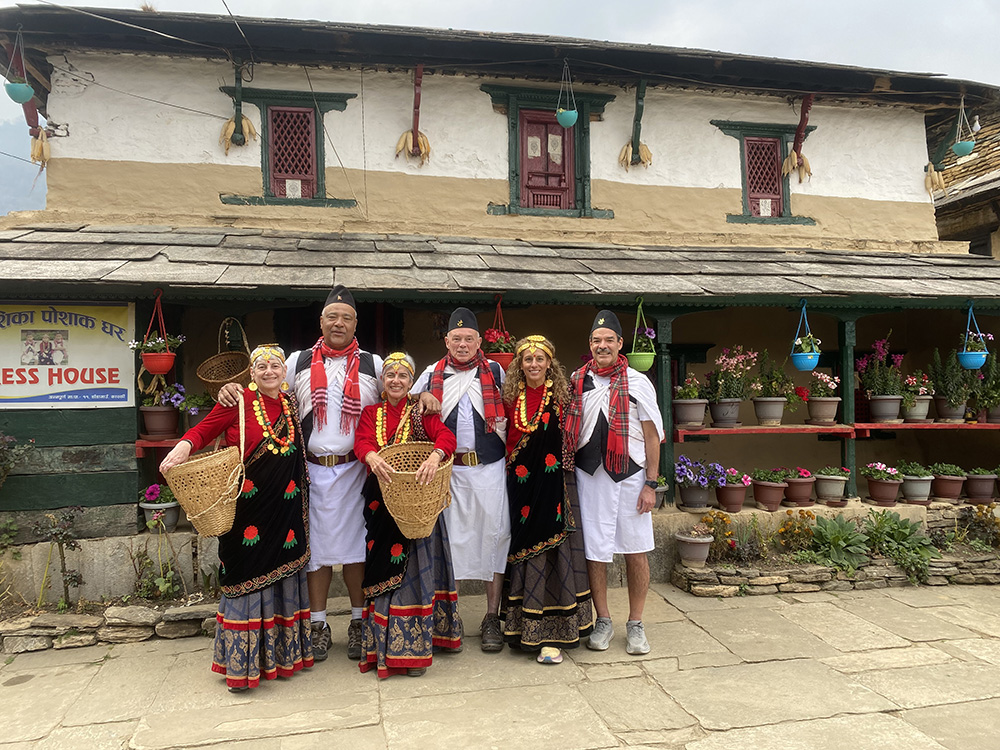 Travellers in traditional hill costume holding doko baskets outside a village house in Nepal
